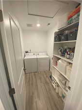 Laundry room with separate washer and dryer and light hardwood / wood-style flooring