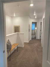 Hallway with dark carpet and a textured ceiling