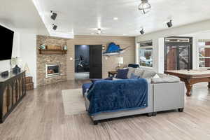 Living room featuring light hardwood / wood-style flooring, wooden walls, a fireplace, a wealth of natural light, and a textured ceiling