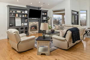 Living room with a stone fireplace, light hardwood / wood-style floors, and a wealth of natural light