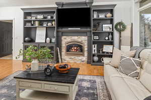 Living room with a stone fireplace and hardwood / wood-style floors