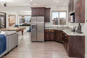 Kitchen featuring a wealth of natural light, sink, pool table, stainless steel appliances, and light stone countertops