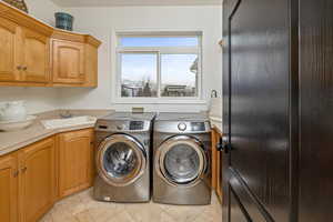 Laundry room featuring cabinets, separate washer and dryer, sink, and light tile patterned floors