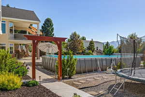 View of swimming pool with a patio, a mountain view, a trampoline, and a pergola