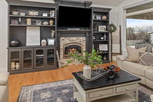 Living room with hardwood / wood-style flooring, vaulted ceiling, and a fireplace