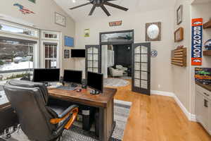 Office area with vaulted ceiling, french doors, ceiling fan, and light wood-type flooring