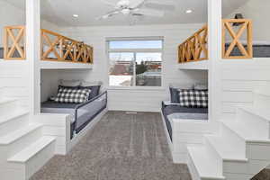 Carpeted bedroom with ceiling fan and wood walls