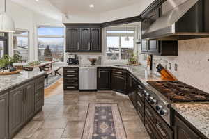 Kitchen with stainless steel appliances, pendant lighting, backsplash, and wall chimney exhaust hood