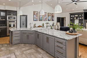 Kitchen with appliances with stainless steel finishes, gray cabinets, sink, and a center island with sink