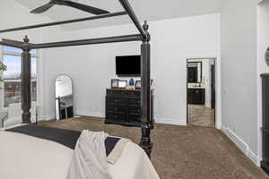 Carpeted bedroom featuring connected bathroom and ceiling fan