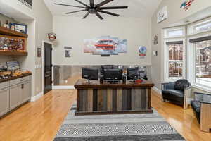 Office area with ceiling fan, lofted ceiling, and light hardwood / wood-style floors