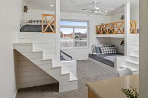 Bedroom with carpet flooring, ceiling fan, and wood walls