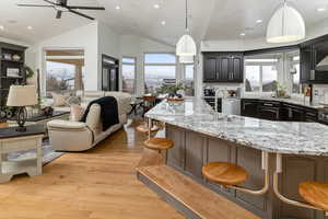 Kitchen featuring tasteful backsplash, a breakfast bar, hanging light fixtures, and a large island with sink