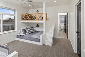 Bedroom featuring ceiling fan, connected bathroom, wooden walls, and carpet floors