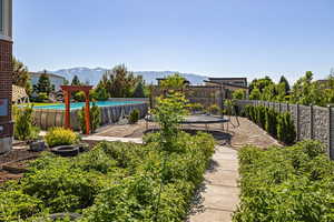 View of yard with a fenced in pool, a mountain view, and a trampoline