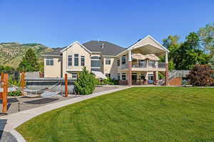 Back of property with a mountain view, a yard, a patio area, and a pool