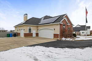 View of front of property featuring a garage and solar panels