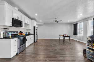 Kitchen with white cabinetry, dark wood-type flooring, ceiling fan, and appliances with stainless steel finishes