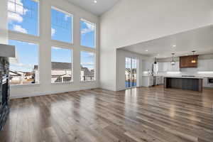 Unfurnished living room with hardwood / wood-style flooring, a towering ceiling, and sink