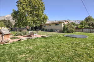 View of yard with a trampoline, a mountain view, and a patio