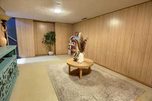 Living area with a textured ceiling and wood walls