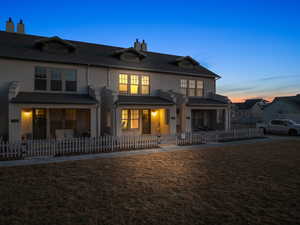 Back house at dusk featuring a yard