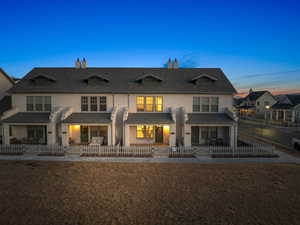 Back house at dusk featuring a patio and a yard