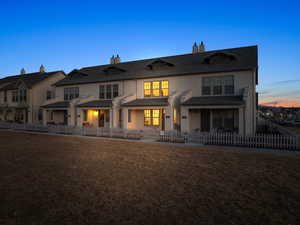 Back house at dusk with a yard