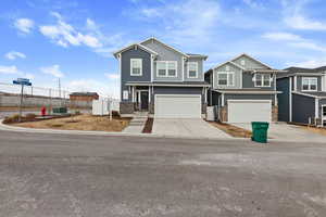 Craftsman inspired home featuring an attached garage, driveway, stone siding, and fence