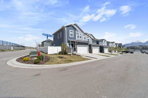 Exterior space with a residential view, fence, an attached garage, a mountain view, and driveway
