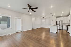 Unfurnished living room with ceiling fan, sink, and dark hardwood / wood-style flooring