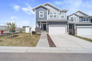 View of front facade with concrete driveway, stone siding, an attached garage, and board and batten siding