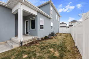 Rear view of house featuring central AC unit, a lawn, and a patio area