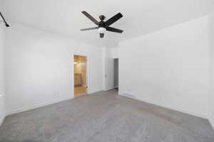 Unfurnished bedroom featuring visible vents, baseboards, ceiling fan, ensuite bath, and light carpet