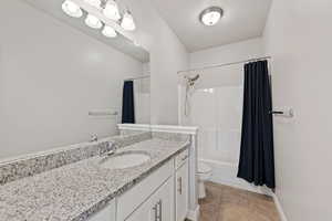 Full bathroom featuring vanity, shower / bath combination with curtain, tile patterned floors, and toilet