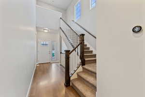 Foyer with wood-type flooring, a healthy amount of sunlight, and a towering ceiling