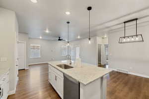 Kitchen featuring sink, hanging light fixtures, dishwasher, an island with sink, and white cabinets