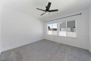 Spare room featuring baseboards, a ceiling fan, and carpet
