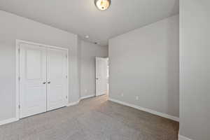 Unfurnished bedroom featuring light colored carpet and a closet