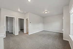 Unfurnished bedroom featuring dark colored carpet and a walk in closet