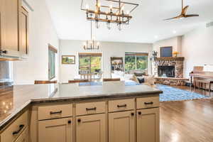 Kitchen with pendant lighting, lofted ceiling, a fireplace, and light hardwood flooring