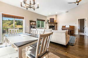 Dining room with a fireplace, lofted ceiling, dark hardwood flooring, and a chandelier