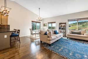 Living room featuring vaulted ceiling, dark hardwood /  floors, and an inviting chandelier