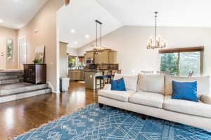 Living room featuring lofted ceiling, dark hardwood floors, and a chandelier