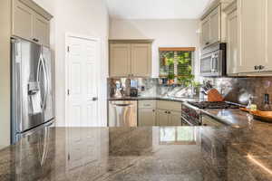 Kitchen featuring backsplash, sink, kitchen peninsula, and appliances with stainless steel finishes