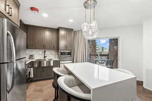 Kitchen with stainless steel appliances, light parquet flooring, hanging light fixtures, and sink