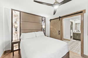 Bedroom featuring sink, light parquet floors, ceiling fan, connected bathroom, and a barn door