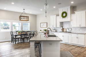 Kitchen with a center island with sink, white cabinetry, and pendant lighting