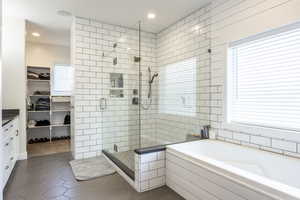 Bathroom with tile patterned flooring, shower with separate bathtub, plenty of natural light, and vanity