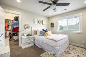 Bedroom featuring dark colored carpet, a spacious closet, ceiling fan, and a closet